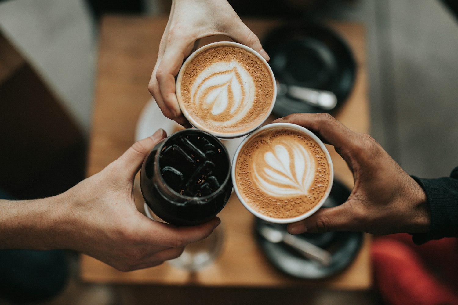 Drie handen die koffiekopjes samenbrengen